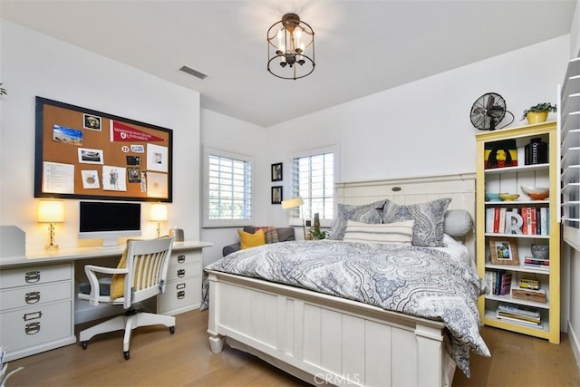 bedroom featuring wood-type flooring and a notable chandelier