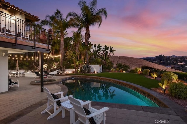 pool at dusk with a mountain view and a patio area