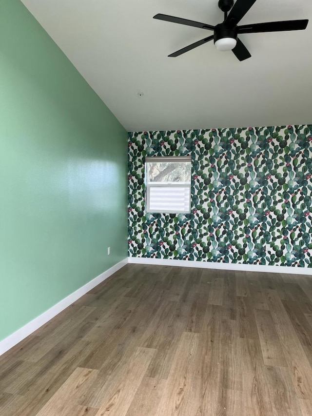 empty room featuring hardwood / wood-style floors, vaulted ceiling, and ceiling fan