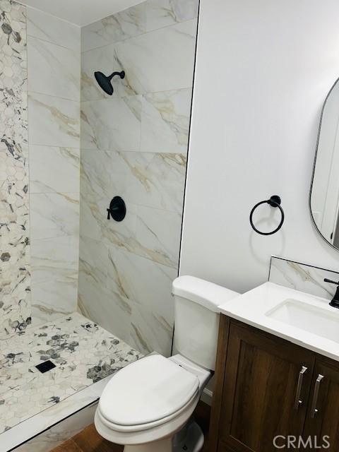 bathroom featuring vanity, toilet, and a tile shower