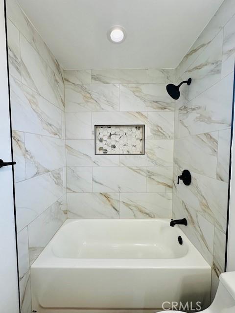 bathroom featuring tiled shower / bath and toilet