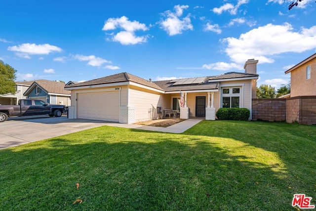 view of front of property featuring a garage, a front yard, and solar panels