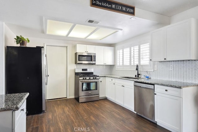 kitchen featuring stone countertops, dark hardwood / wood-style floors, sink, white cabinets, and stainless steel appliances