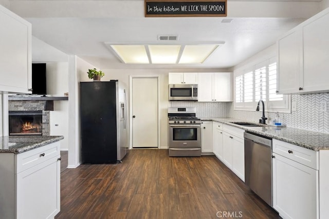 kitchen with white cabinetry, sink, dark stone counters, and appliances with stainless steel finishes