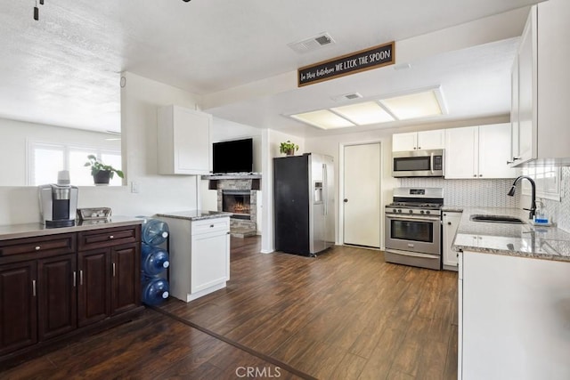 kitchen with appliances with stainless steel finishes, sink, white cabinets, and kitchen peninsula