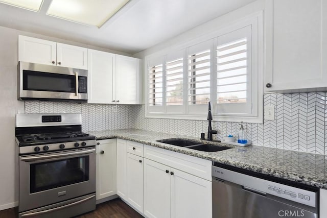 kitchen with light stone counters, appliances with stainless steel finishes, sink, and white cabinets