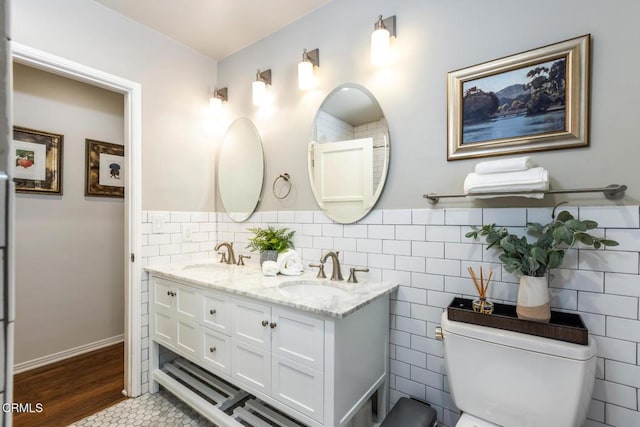 bathroom with vanity, toilet, and tile walls