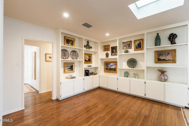 unfurnished living room with a skylight, ornamental molding, and wood-type flooring