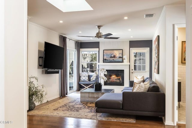 living room featuring a skylight, crown molding, wood-type flooring, and ceiling fan