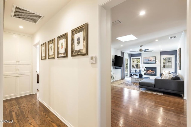 corridor with dark hardwood / wood-style floors and a skylight