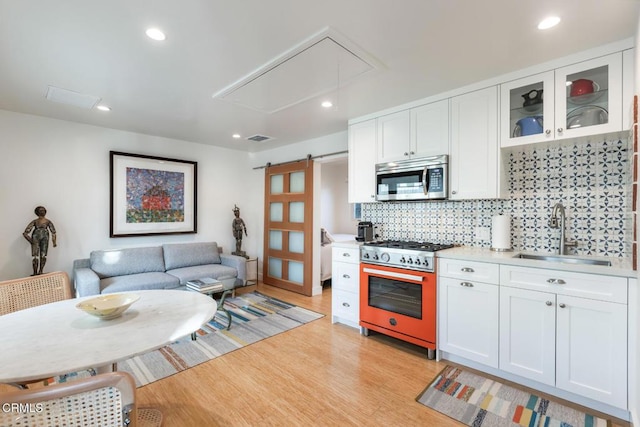 kitchen featuring white cabinetry, a barn door, sink, and range