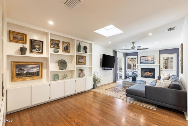 living room featuring hardwood / wood-style floors, a skylight, and ceiling fan