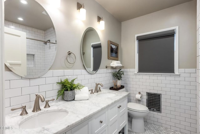 bathroom with tile patterned floors, vanity, toilet, and tile walls