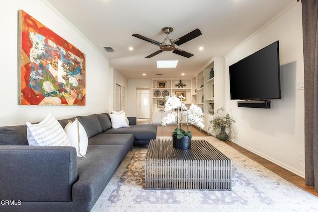 living room featuring wood-type flooring, crown molding, ceiling fan, and built in shelves