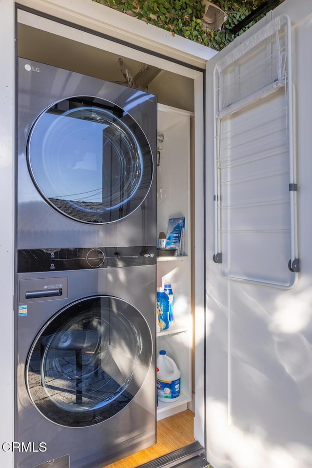 clothes washing area featuring stacked washer and clothes dryer and hardwood / wood-style floors