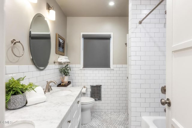 full bathroom with tile walls, tile patterned flooring, vanity, toilet, and tiled shower / bath