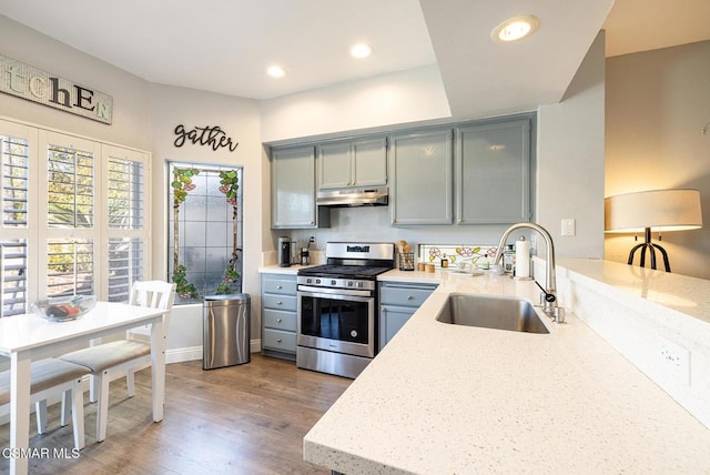 kitchen with gray cabinets, sink, light hardwood / wood-style floors, light stone countertops, and stainless steel range with gas stovetop