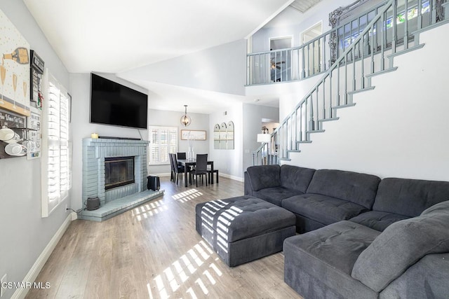 living room featuring lofted ceiling, a brick fireplace, and wood-type flooring