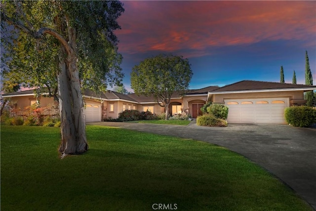 ranch-style house featuring a garage and a yard