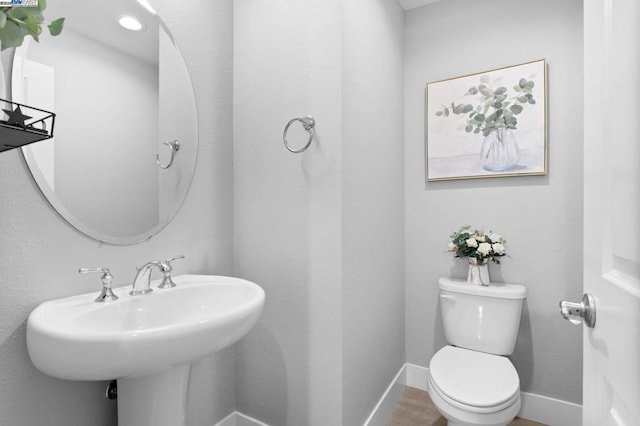 bathroom with hardwood / wood-style flooring, sink, and toilet