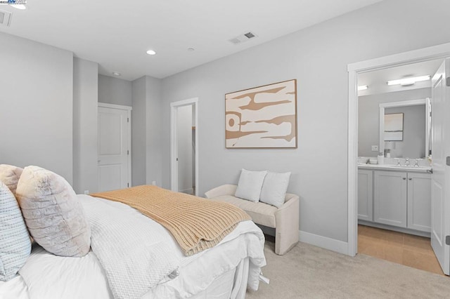 bedroom featuring sink, light carpet, and ensuite bath