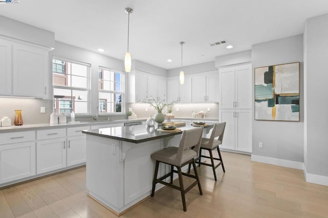 kitchen featuring white cabinetry, a kitchen island, sink, and a kitchen bar