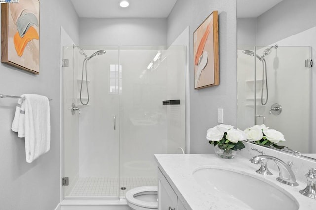 bathroom featuring vanity, a shower with shower door, and toilet