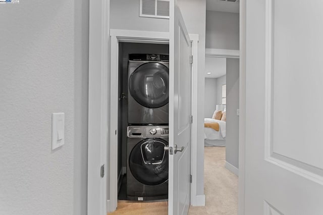 clothes washing area with stacked washer / dryer and light colored carpet