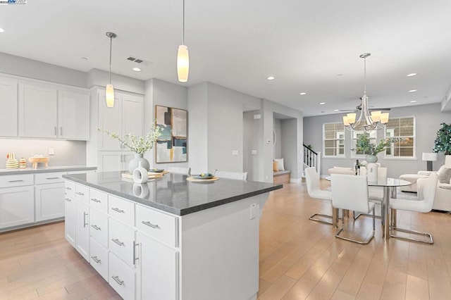 kitchen featuring white cabinetry, an inviting chandelier, a center island, light hardwood / wood-style floors, and decorative light fixtures