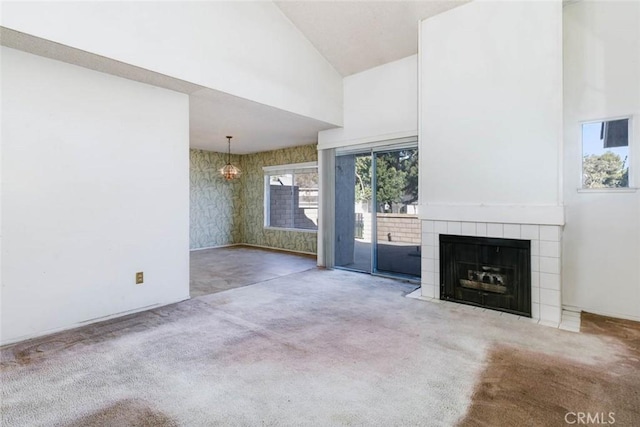 unfurnished living room with a tile fireplace, carpet, and high vaulted ceiling