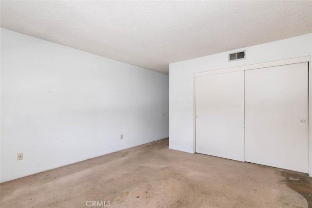 unfurnished bedroom with light carpet, a closet, and a textured ceiling