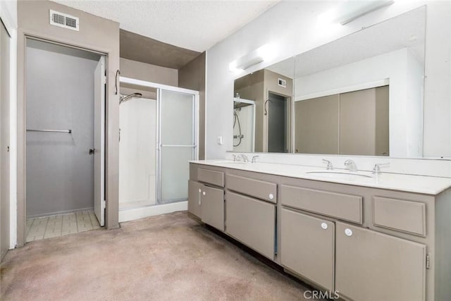 bathroom featuring vanity, a shower with shower door, and a textured ceiling