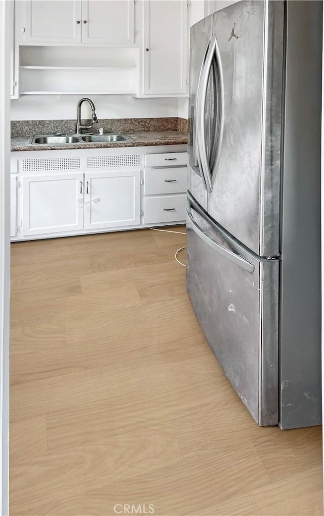 kitchen with sink, white cabinets, and stainless steel refrigerator