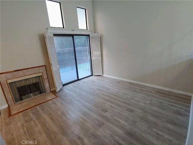 unfurnished living room with a premium fireplace, a high ceiling, and light wood-type flooring