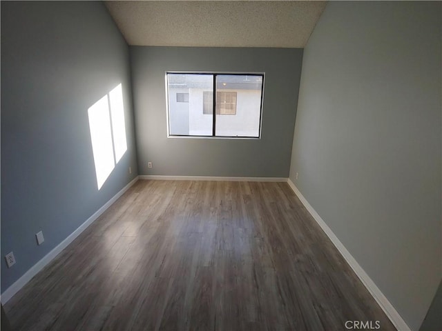 spare room featuring dark hardwood / wood-style flooring and a textured ceiling