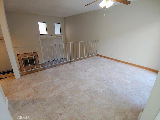 spare room with ceiling fan and a fireplace