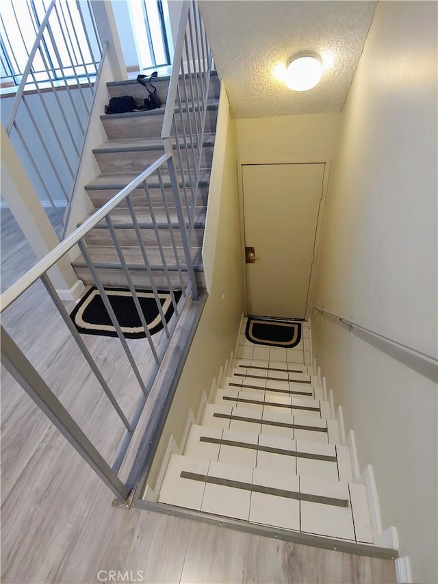 staircase with hardwood / wood-style floors and a textured ceiling