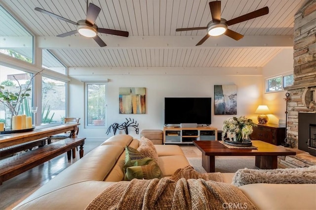 living room featuring lofted ceiling with beams, a stone fireplace, wooden ceiling, and ceiling fan