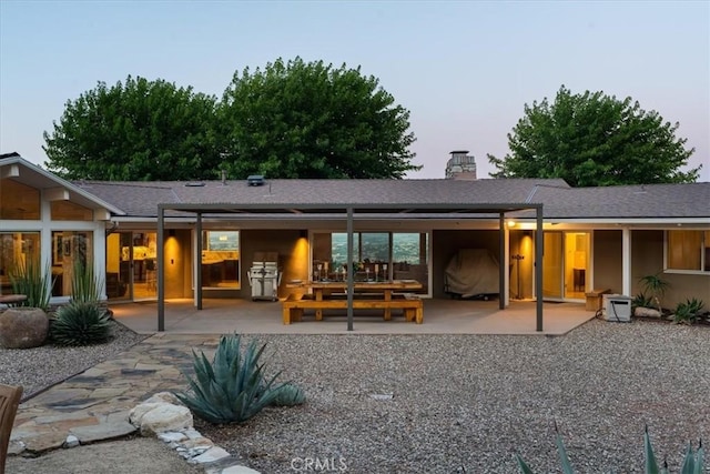 back house at dusk with a patio area