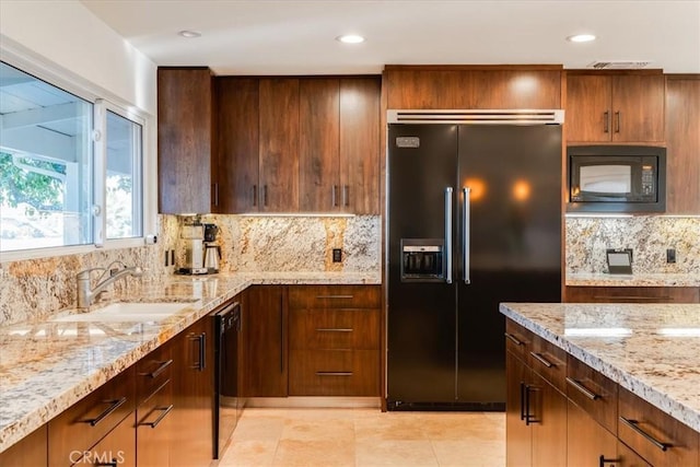 kitchen with sink, decorative backsplash, light tile patterned floors, black appliances, and light stone countertops