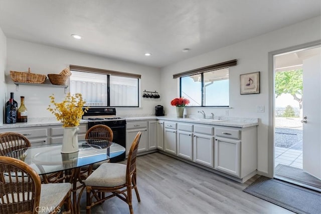 kitchen with sink, gas range oven, and light hardwood / wood-style floors