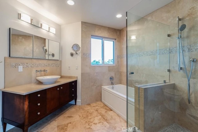 bathroom featuring independent shower and bath, vanity, tile walls, and decorative backsplash