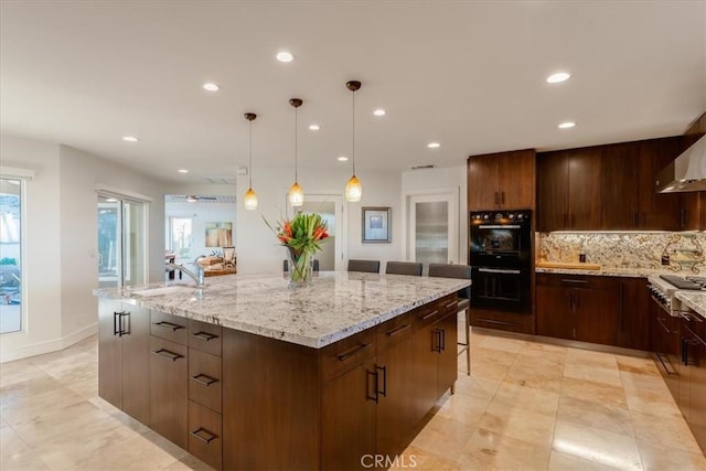 kitchen featuring sink, hanging light fixtures, a kitchen breakfast bar, black double oven, and a large island