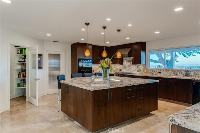 kitchen featuring pendant lighting, sink, light stone countertops, a kitchen island, and decorative backsplash