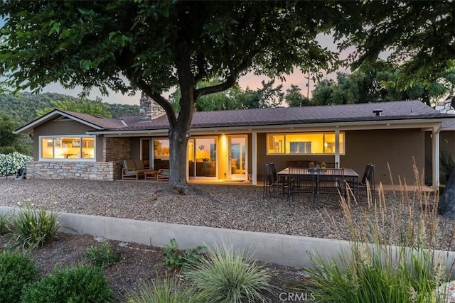 back house at dusk featuring a patio