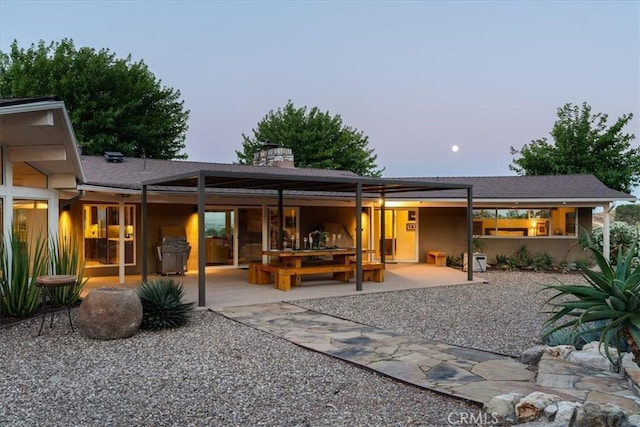 back house at dusk with a patio area