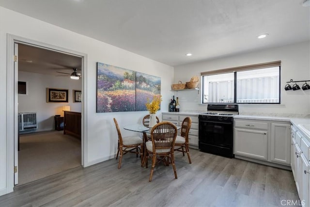 kitchen with gas range oven, light wood-type flooring, and white cabinets