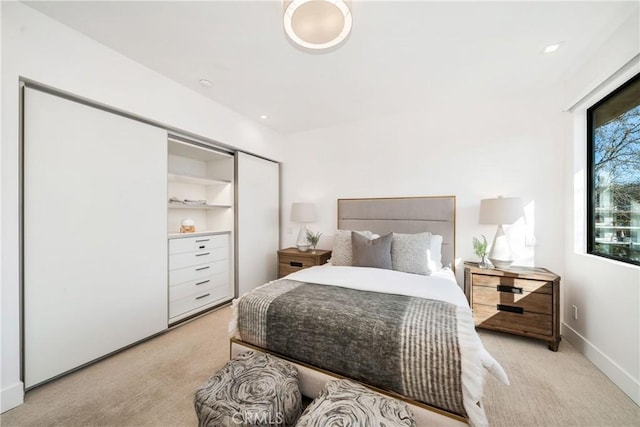 bedroom with light carpet, baseboards, and a closet