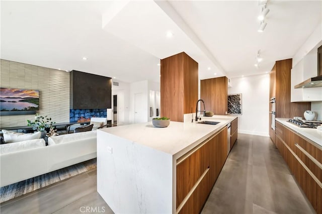 kitchen featuring a large island, modern cabinets, brown cabinets, open floor plan, and a sink