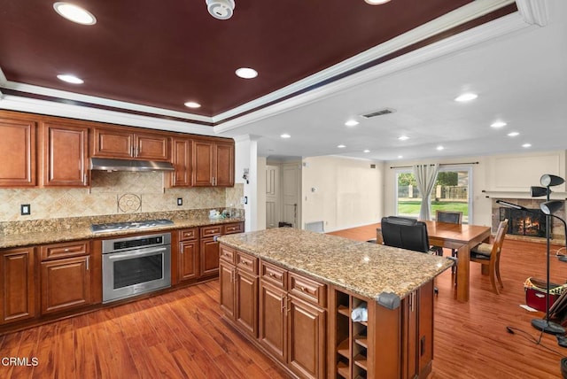 kitchen with stainless steel appliances, ornamental molding, a center island, and light hardwood / wood-style flooring